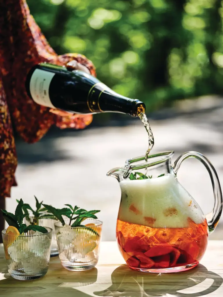 Wine is poured into a pitcher of sangria in a...