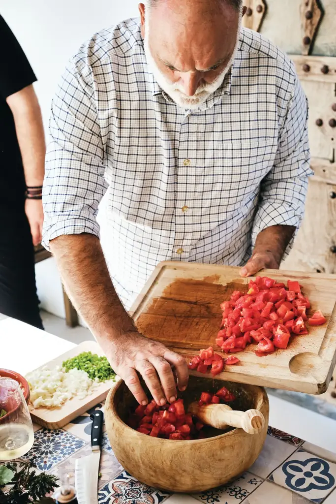 Chef JosÃ© AndrÃ©s puts chopped tomatoes into a bowl as...