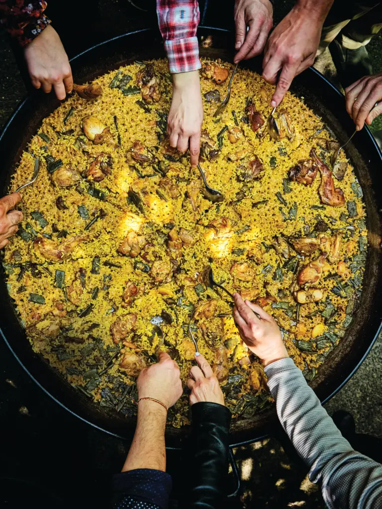 Hungry dining companions dip their spoons into Paella Valencia in...