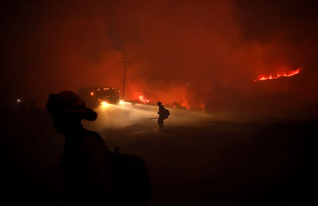 Firefighters work to put out embers from the El Dorado...