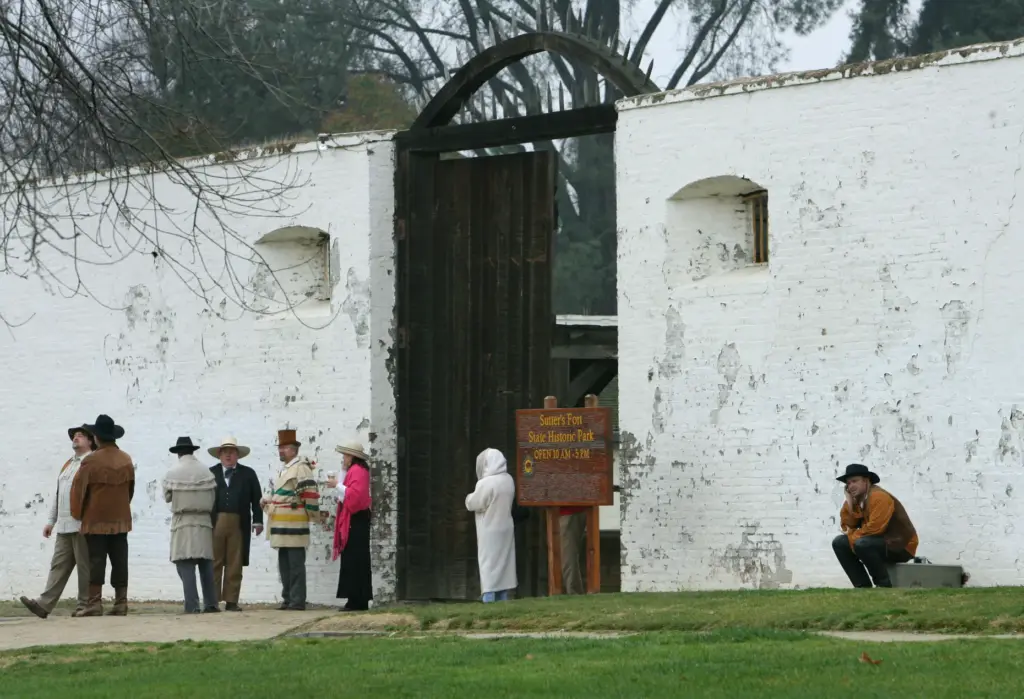 Docents dressed in period costumes wait for a group of...