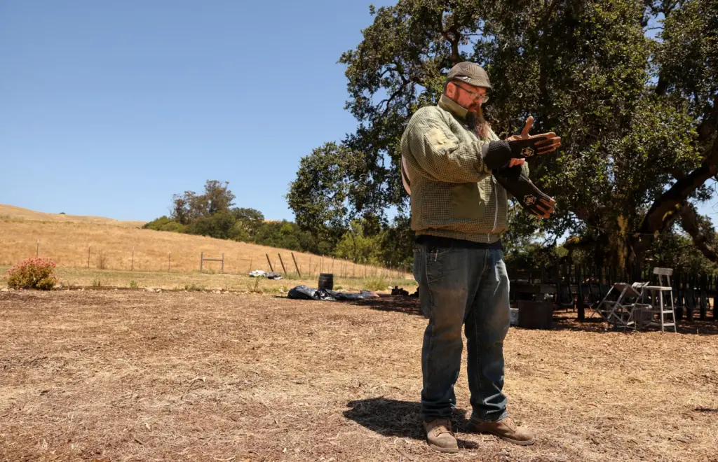 Don Merrill, owner of No Bull Beekeeping, puts on his...