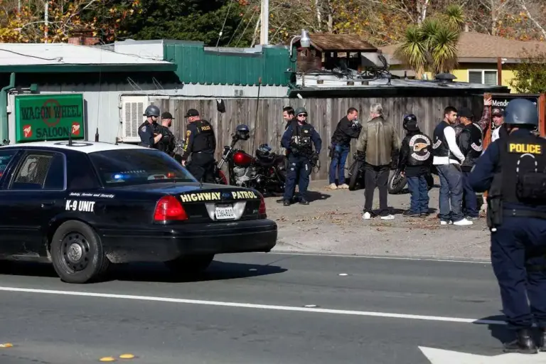 Law enforcement officers from various agencies search motorcycles outside the...