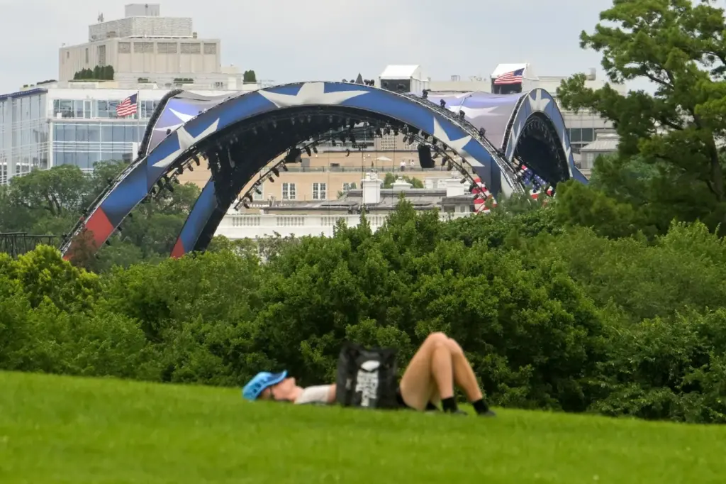 A man rests on the grass near the Washington Monument...