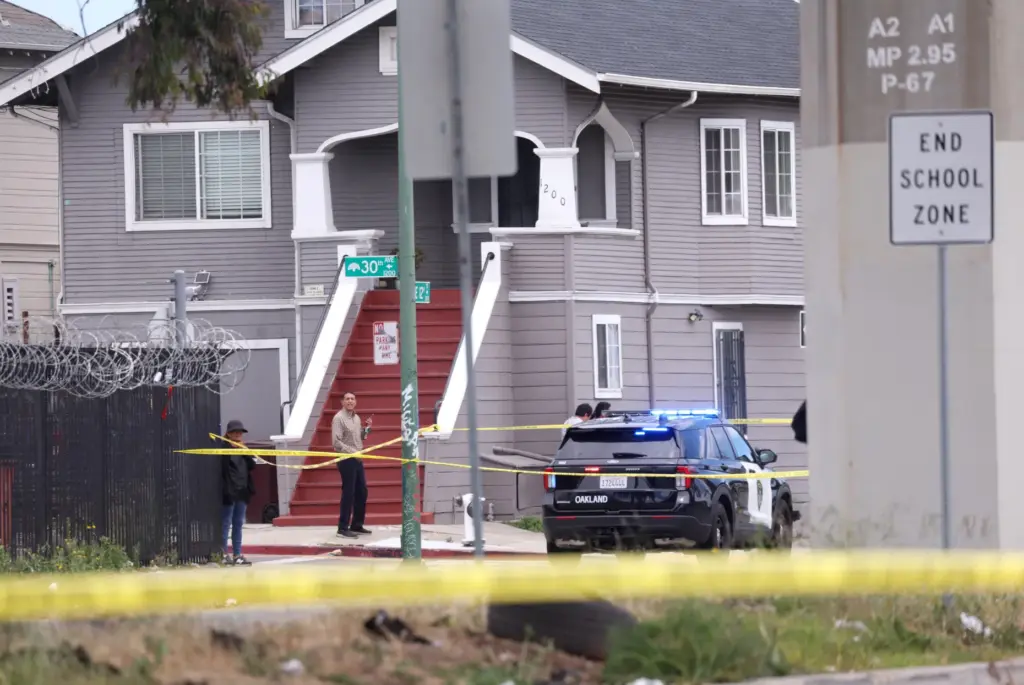 Bystanders watch as Oakland police investigate a double fatal crash...