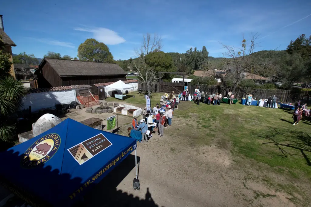 People visit tables in a circle near the barracks during...