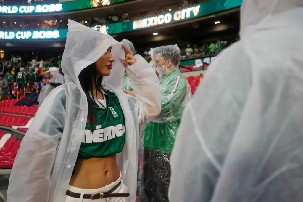 A fan wears a poncho as it rains ahead of...
