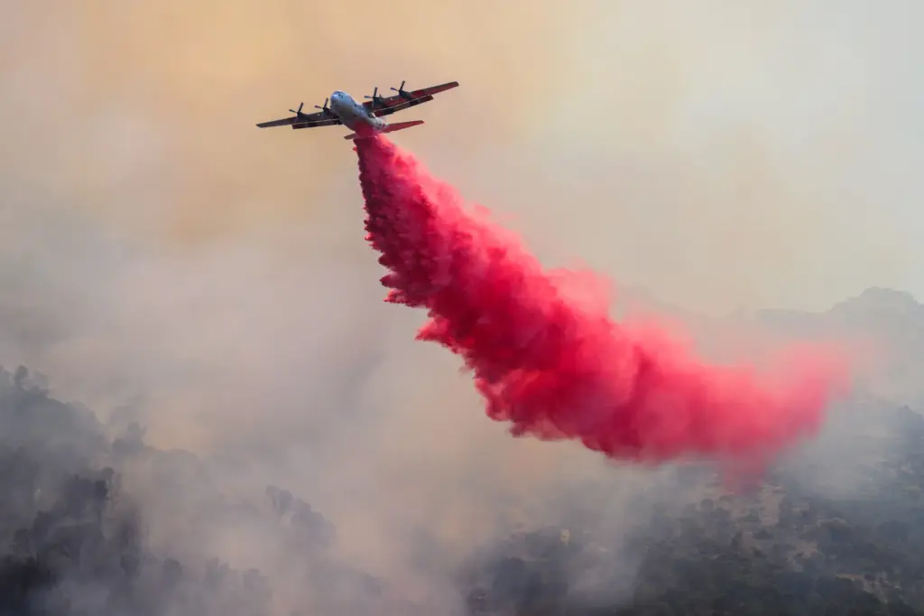 A Cal-Fire C-130 airtanker drops fire retardant while battling the...