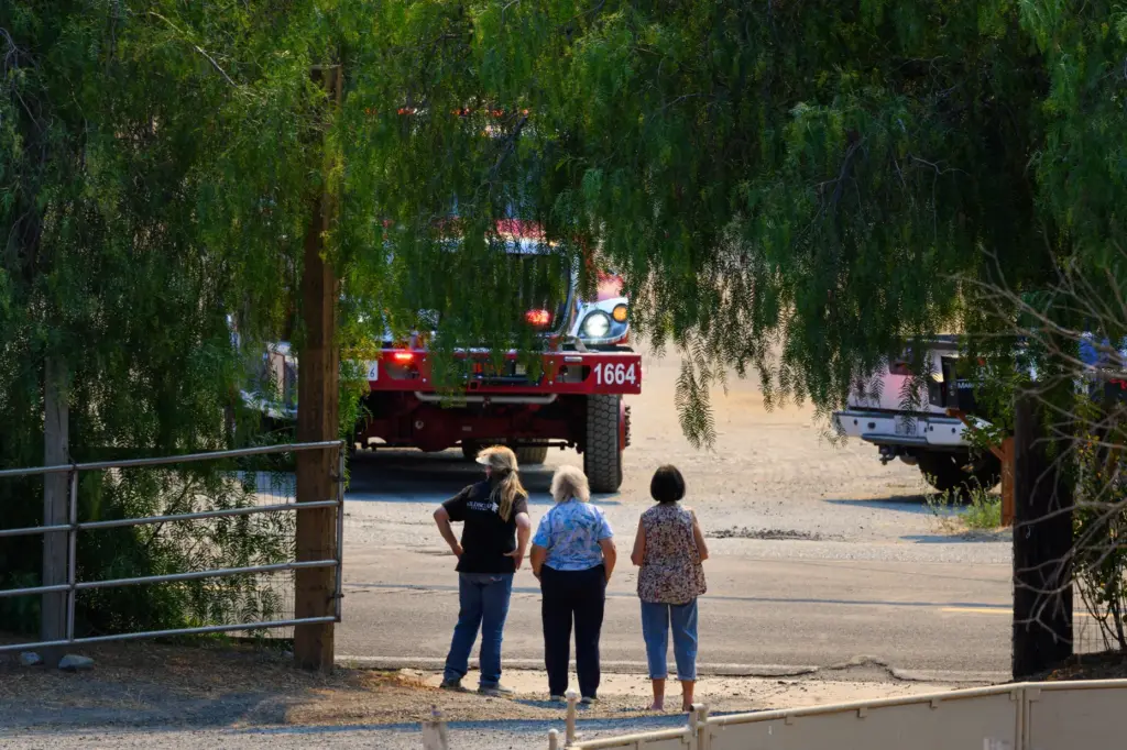 Residents watch as fire crews arrive to battle the Morgan...