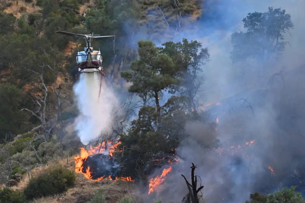 A helicopter drops water while battling the Morgan Fire in...
