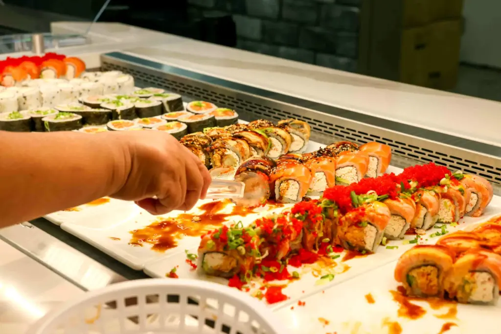 A customer serves herself sushi from the sushi buffet during...