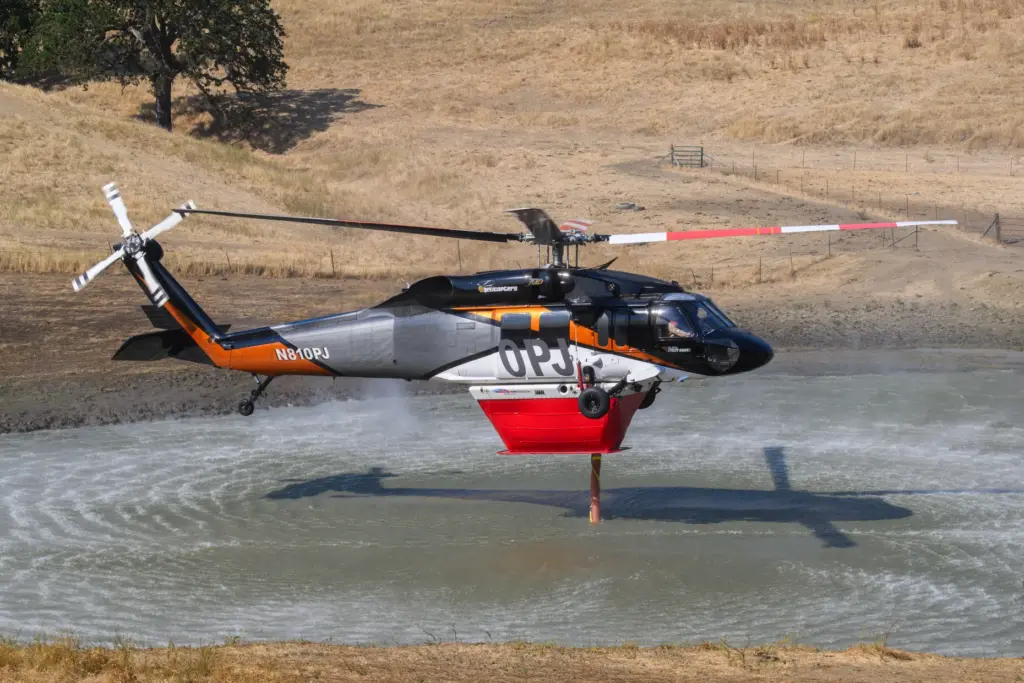 A helicopter refills their water tanks from a wateringhole while...
