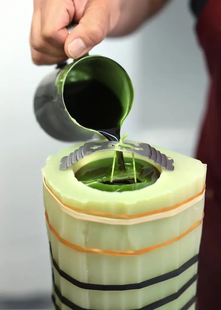 A worker pours wax into a mold for a cactus candle.