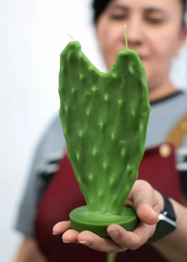 A worker holds a cactus candle at Happy Organics' studio.