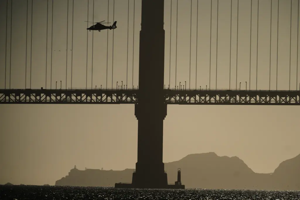 A helicopter goes past the Golden Gate Bridge as part...