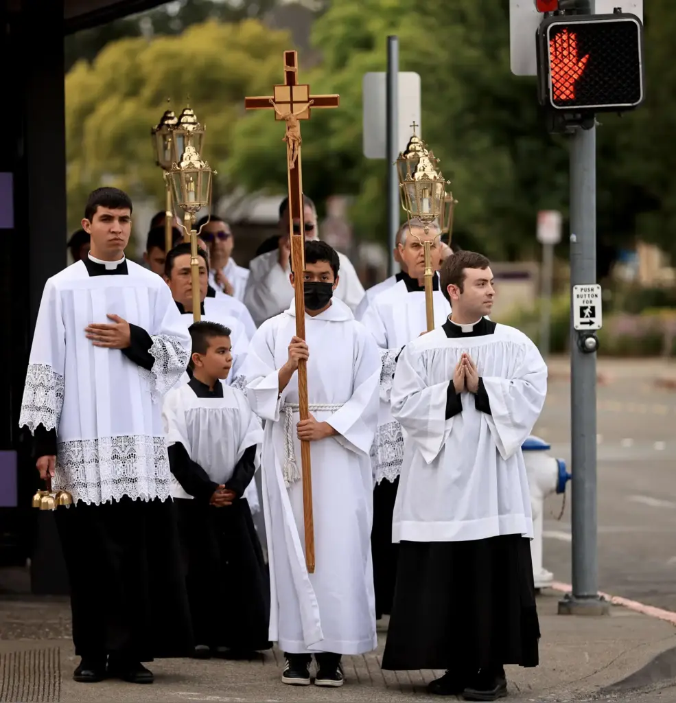 Acolytes and deacons lead the procession of the Eucharist, Thursday,...