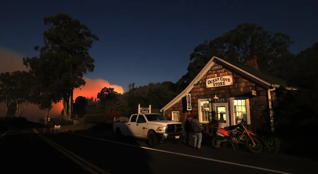 Friends gather at Ocean Cove Store in the evacuation zone,...