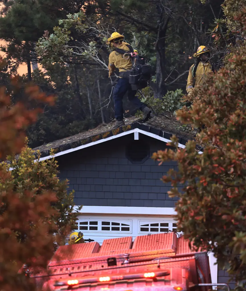 Cal Fire personnel remove trees and debris around a home...