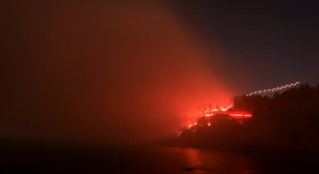 The Woodside Fire burns down to the Pacific Ocean north...