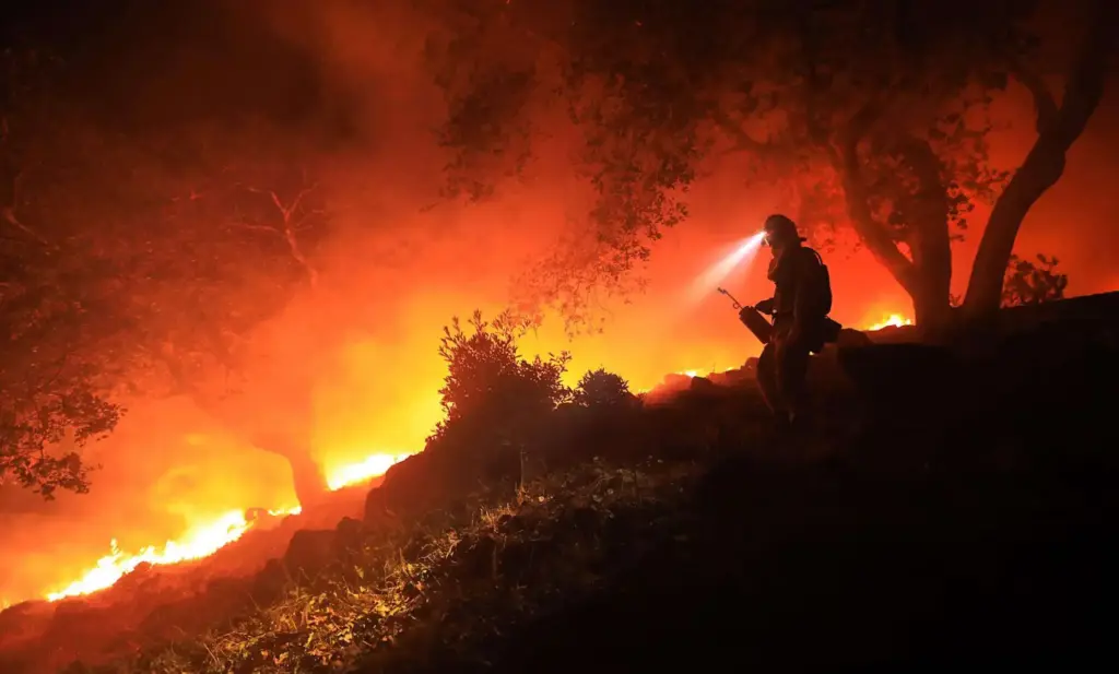 A San Diego Cal Fire firefighter monitors a flare up...