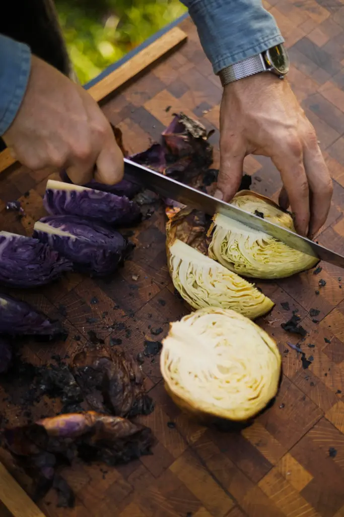 Chef Lee Desrosiers slices cabbage he slow-roasted over coals. (Conor...
