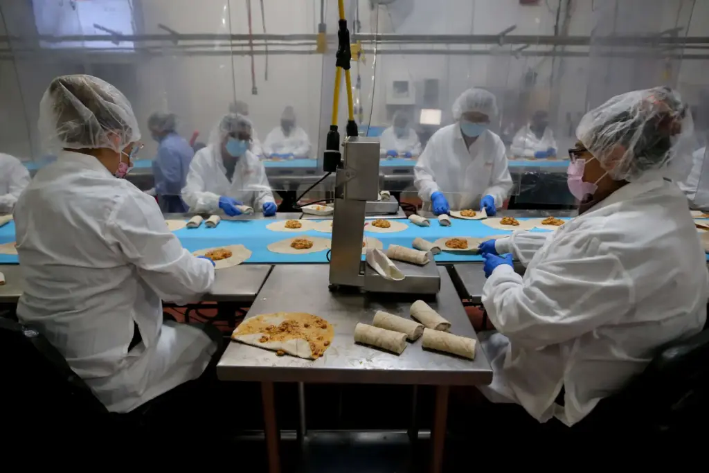 Employees roll up bean and cheese burritos in the Amy’s...