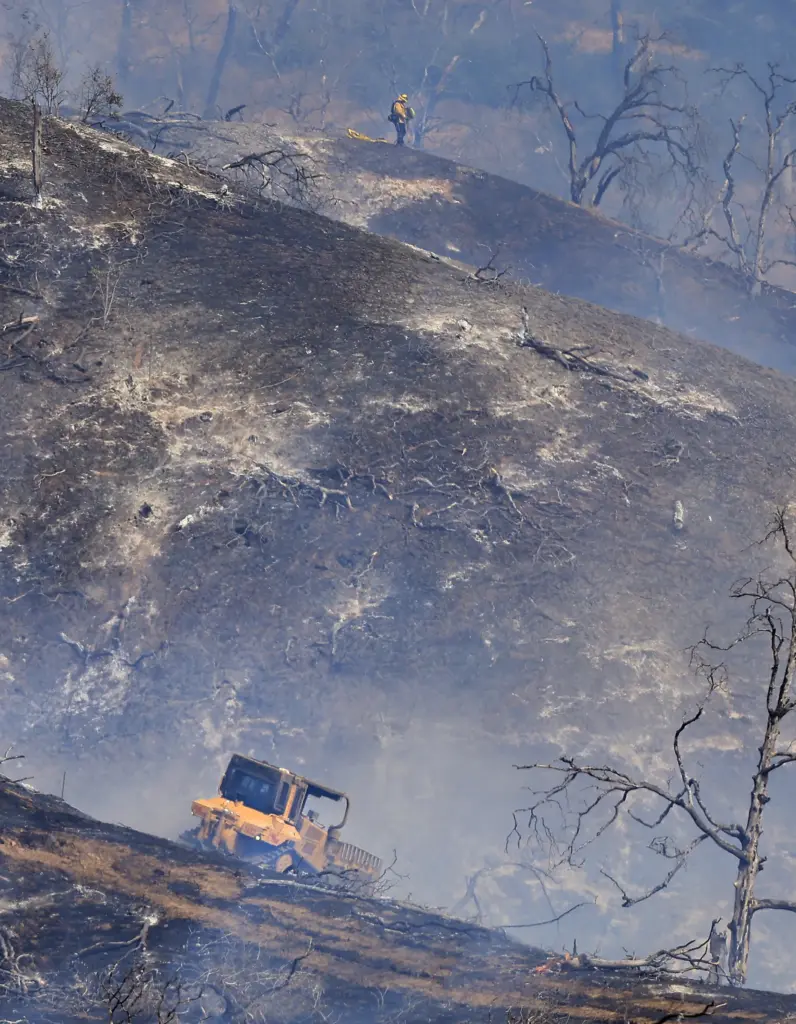 A Cal Fire dozer cuts across the Steele Fire, to...
