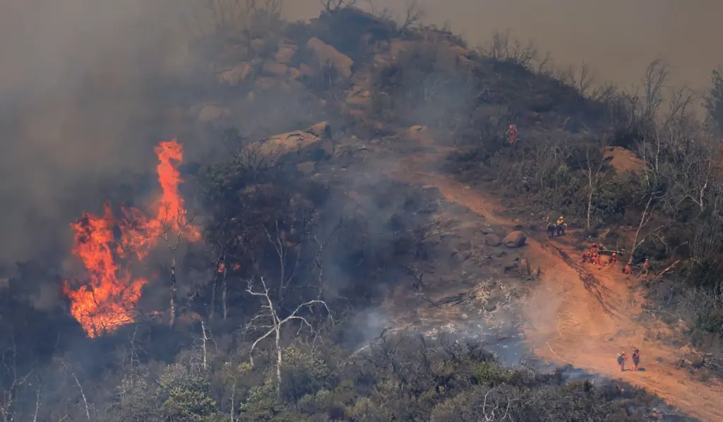 Flames encroach on a fire break at the Lucas Fire...