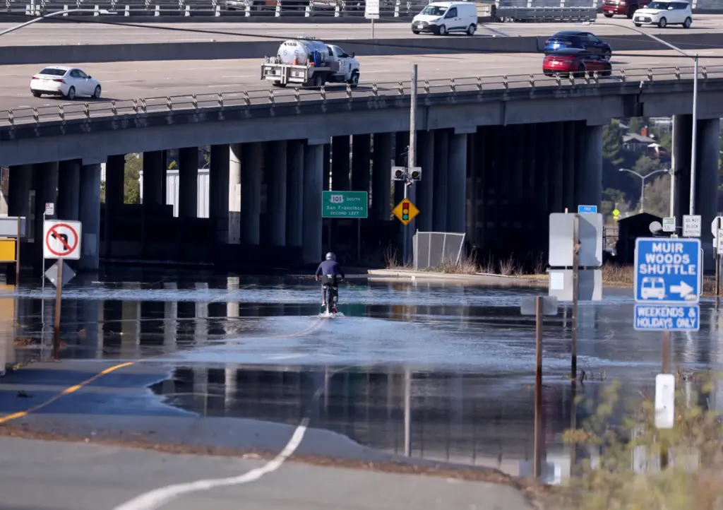 A bicyclist rides through high tide flood waters near the...