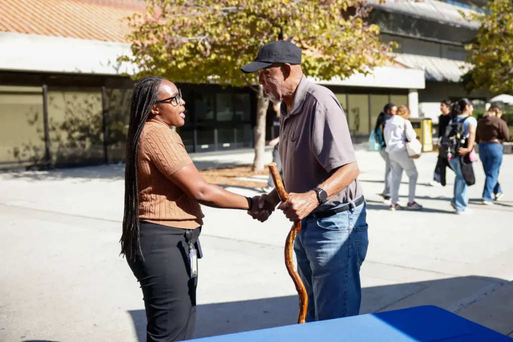 Dr. Kiamsha Bynes shakes hands with Dr. John Carlos at...