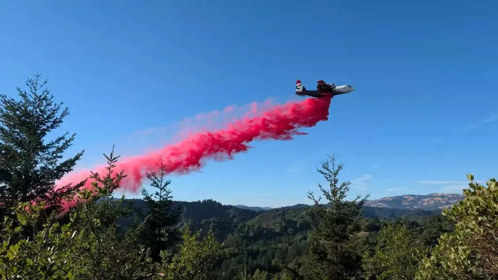 A Cal Fire aircraft dumps fire retardant to protect containment...