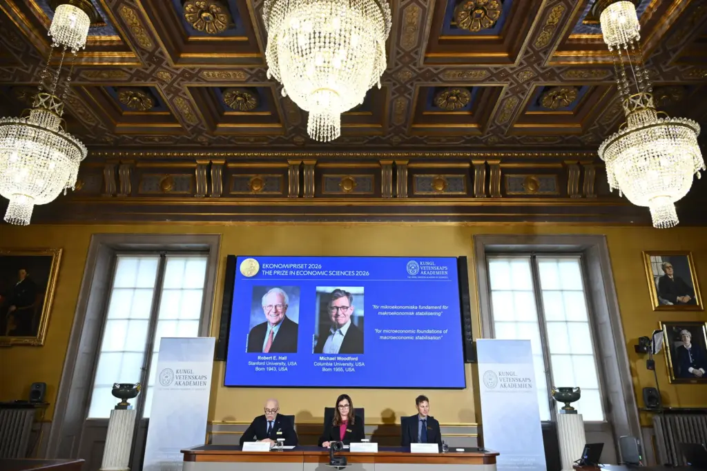 Portraits of Robert E. Hall and Michael Woodford are shown on the screen.